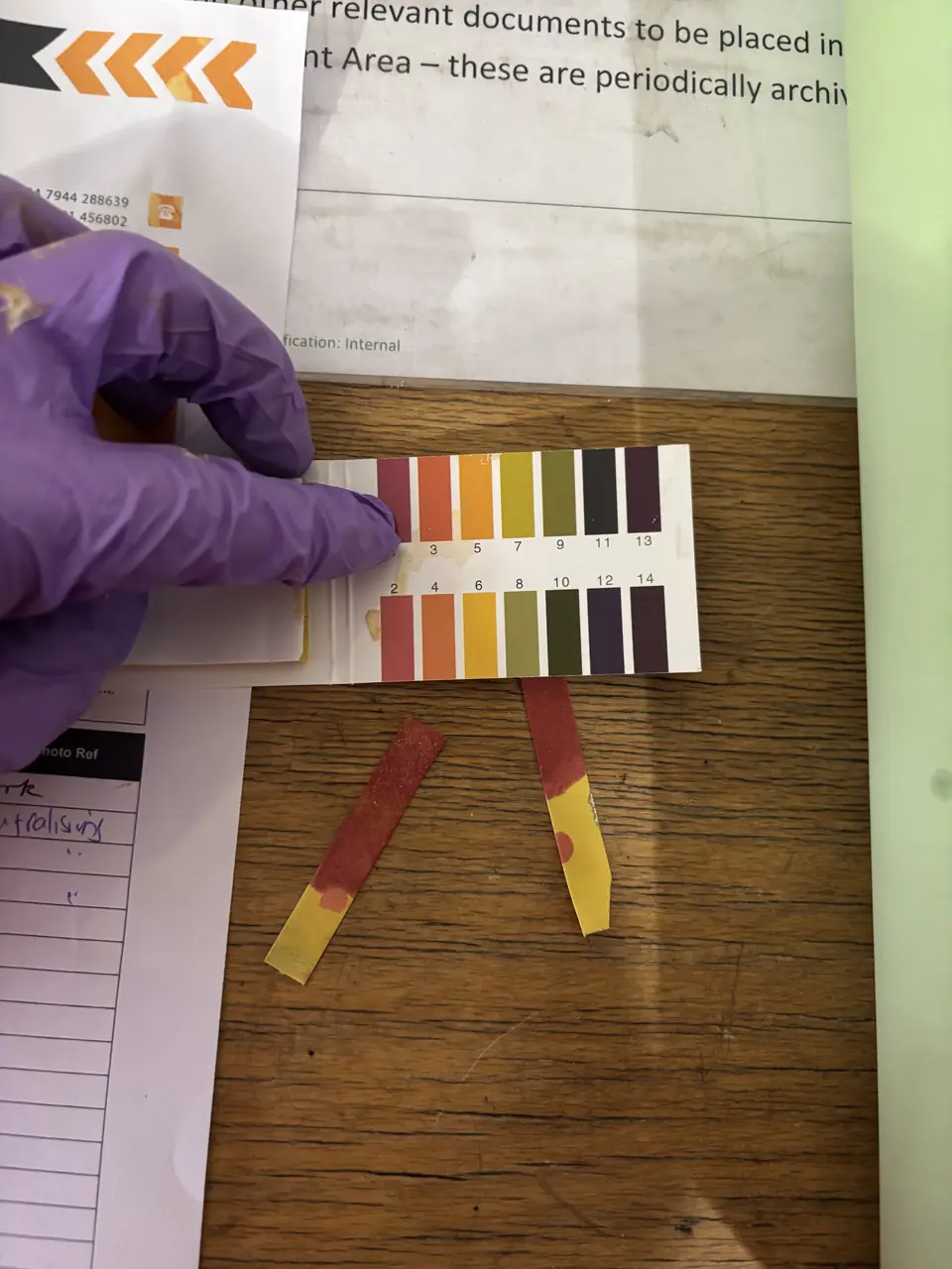 pH indicator strip compared against a colour chart during testing